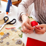 Senior women sews by hand and making heart shape ornament.